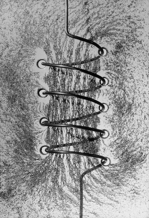 Solenoid creating magnetic flow, iron filings aligning with the flow direction.